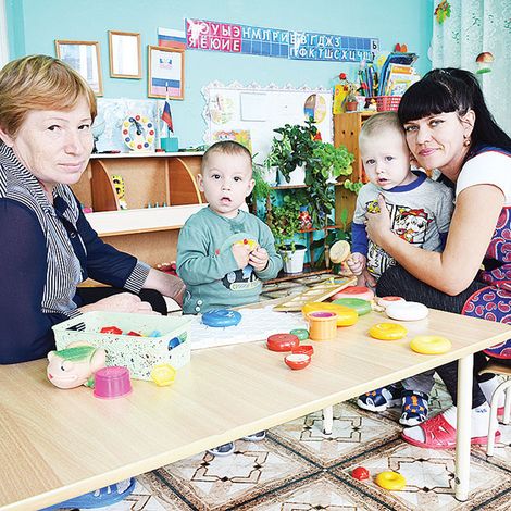 Воспитатель Е. А. Афонченко и помощник воспитателя И. С. Стрюкова с самыми маленькими воспитанниками.